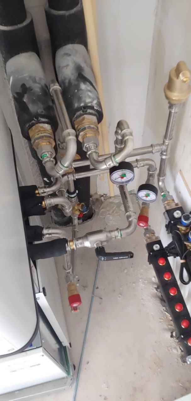 Pijpleidingen en kleppen met drukmeters in een technische ruimte.